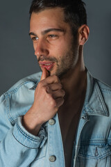 Picture of a young handsome macho man with abs and open denim jacket and jeans.