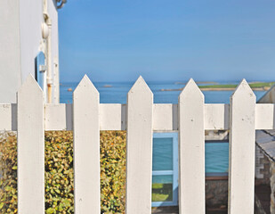 closeup on white fence of a hose in Brittany- France  in front of the seashore under blue sky