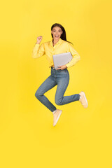 Fototapeta na wymiar Joyful Lady Jumping Holding Laptop Shaking Fists Over Yellow Background