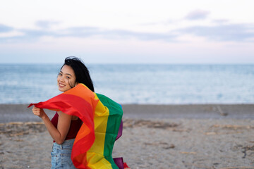 Happy girl with a pride flag at the beach. LGBT community