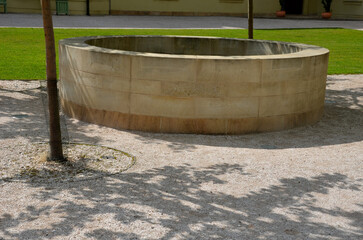stone round fountain with a protective grid of twisted prisms. forged steel bars go spiraled at the...