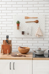 Cutting boards with knife and bowls on counter near white brick wall