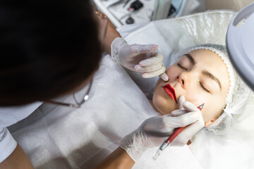 Permanent makeup artist and her client during lip blushing procedure