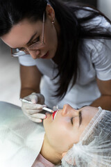 Permanent makeup artist and her client during lip blushing procedure