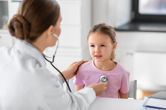 medicine, healthcare and pediatry concept - female doctor or pediatrician with stethoscope and little girl patient on medical exam at clinic