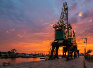 Historic harbour cranes on riverside boulevards in Szczecin during a dramatic sunrise © Mike Mareen