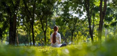 Woman relaxingly practicing meditation in the forest to attain happiness from inner peace wisdom...