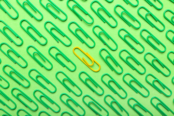 Yellow and green paper clips on color background