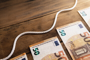 Wavy white rope above several fifty euro banknotes.