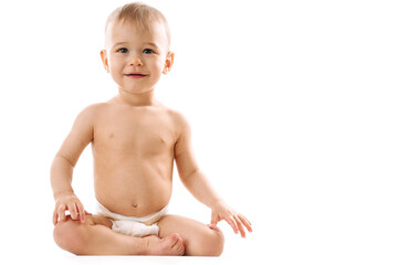 Curious healthy little boy in diaper sitting and smiling.