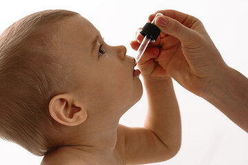 Mother gives vitamin D to her little son.