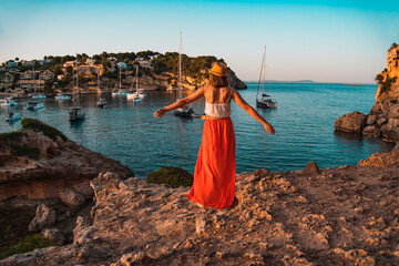 Young woman on holiday with her arms stretched out happily looking at the landscape, in the cove of...