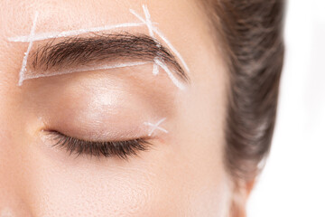 Female face during professional eyebrow mapping procedure before permanent makeup