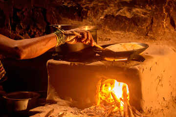 indian village woman cooking making roti bread in sitting kitchen 