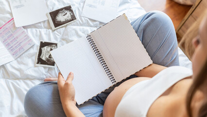 Baby list pregnant woman. Young pregnancy mother holding notepad. Pregnant lady writing check list of baby. Concept of maternity, expectation.