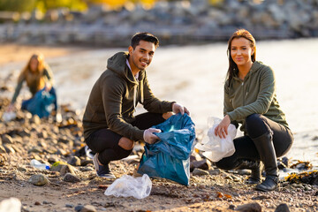 Team of dedicated and smiling volunteers collecting plastic garbage at beach