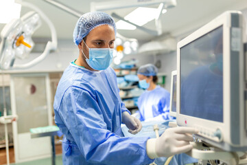 Anesthetist Working In Operating Theatre Wearing Protecive Gear checking monitors while sedating...