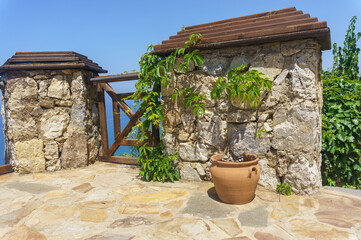 Large clay pot by a stone wall framed with wild grapes
