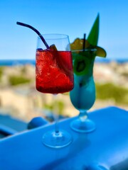 Cocktail Blue Lagoon and Negroni with ice on the background of the beach