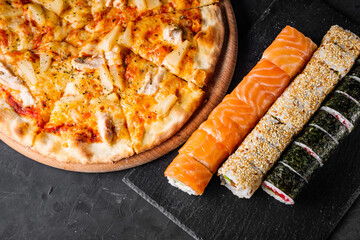 set of pizza and sushi rolls on a dark stone background