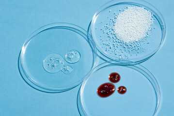 Cosmetic swatches. Appearance of the texture of the cream, red mask, foam and granules in petri dish on a blue background. Natural skincare products. Beauty concept for face and body care