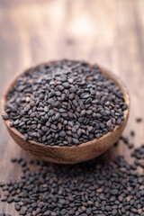 Bio natural black sesame seeds on wooden bowl.