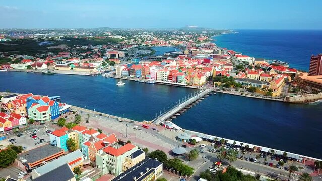 Truck right aerial view of the Otrobanda and Punda districts of Willemstad, Curacao, Dutch Caribbean island on a sunny day. Queen Emma Bridge in St. Anne's Bay
