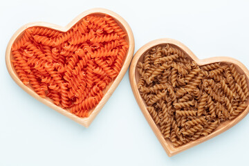 Red lentil fusilli pasta in a heart shaped wood bowl.