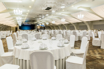 Elegant banquet hall interior prepared for feast with served tables and stage