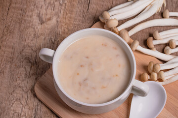 Mushroom cream soup in a white cup on the wooden floor.