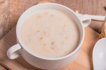 Mushroom cream soup in a white cup on the wooden floor.