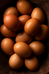 Red hen eggs on dark rustic table, organic food ingredients
