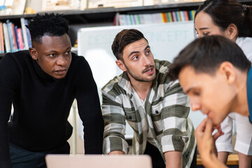 Young diverse creative designer team watching project on laptop. discussing and brainstorming work together in the office studio. sharing idea with colleagues.