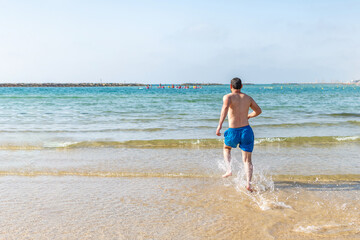 man playful on paradise beach having fun playing splashing water.