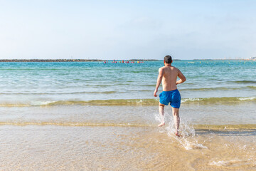 Fototapeta na wymiar man playful on paradise beach having fun playing splashing water.