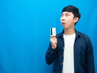 Man blue shirt showing credit card feel excited looking at copy space blue background