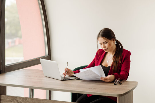 Successful Business Woman Dressed In Red Jacket Is Working With A Laptop In The Office