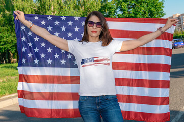 Portrait of smiling pretty young woman holding waving American flag. USA celebrate 4th of July.