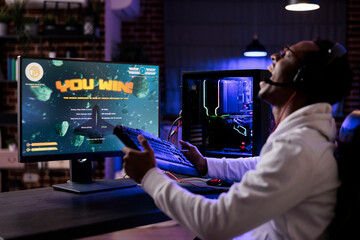 Joyful man winning online video games tournament on pc, streaming action gameplay with multiple...