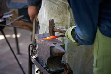 Closeup of two blacksmiths working in a forge.