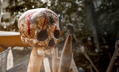 Impaled upper part of the skeleton of a human skull on a wooden pole with smeared red streaks of...