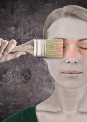 Frau mit einem Malerpinsel schminkt Ihr Gesicht