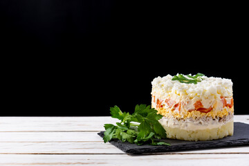 Traditional Russian layered salad Mimosa on wooden table and black background. Copy space