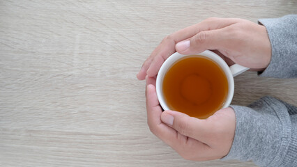 male hands touching a white cup of tea