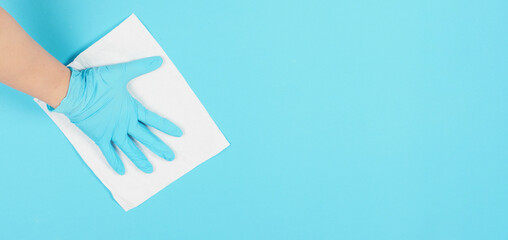 Top view.Hand is wiping and hold white paper tissue on blue background. Hnad wear blue nitrile disposable glove .Empty space for text . - obrazy, fototapety, plakaty