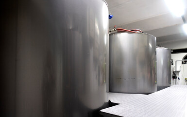 Промышленный интерьер современной пивоварни с хромированными цилиндрическими металлическими пивными баками. Частная микропивоварня.
