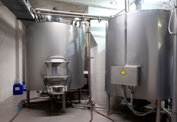 Fototapeta na wymiar Промышленный интерьер современной пивоварни с хромированными цилиндрическими металлическими пивными баками. Частная микропивоварня. 