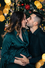 Loving couple at the expectation of a baby. A man and a woman are sitting near a Christmas tree.