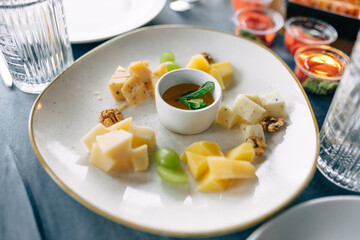 cutting different types of cheeses with nuts and honey on a plate, delicious snack