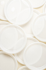 Disposable white plastic tableware on a beige background. The concept of nature pollution